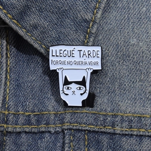 Detailed close-up of a funny cat enamel pin with a quote on blue denim jacket