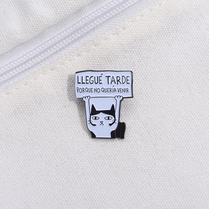 Detail of cartoon cat enamel pin with Spanish slogan on white canvas background