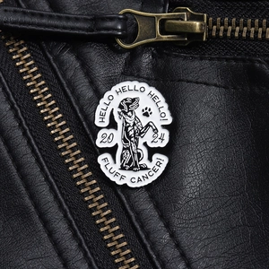 Detail of an enamel dog brooch with Hello text on a black leather jacket collar