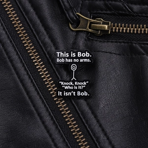 Close-up of This is Bob funny enamel pin badge pinned on a black leather jacket