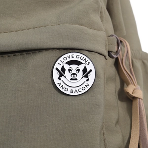 Detail of I Love Guns and Bacon enamel pin on green canvas bag with pig and gun graphics