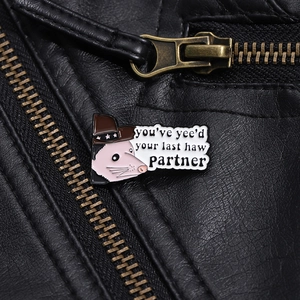 Nahaufnahme der Emaille-Anstecknadel mit Opossum-Cowboy auf einer schwarzen Lederjacke