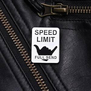 Detail view of Speed Limit enamel pin with shaka gesture on black leather jacket