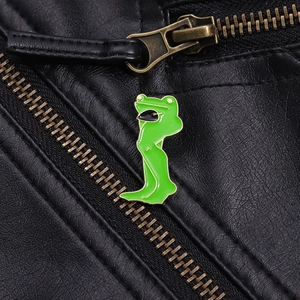 Détail d'un pin's en émail grenouille amusant sur une texture de veste en cuir noir
