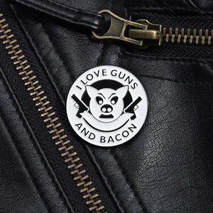 Macro detail of 'I LOVE GUNS AND BACON' pig enamel pin on a black leather jacket texture