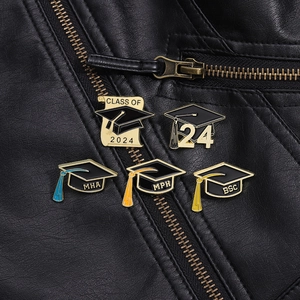 Close-up of five enamel graduation pins showing Class of 2024 and tassels on a leather jacket