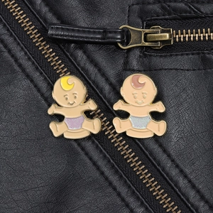 Close-up of cute twin baby enamel pins pinned on a black leather jacket zipper area