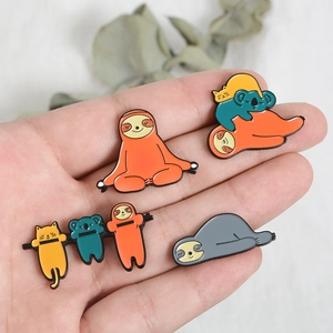 Exquisite sloth enamel pin set featuring cartoon koala and cat on hand for size