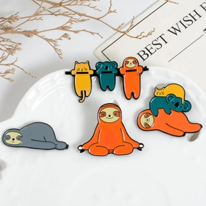 Detail view of cute enamel sloth and koala animal brooches on a white ceramic plate