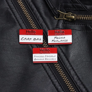 Three enamel pins with Friends show quotes pinned on a black leather jacket collar