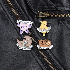 Cute enamel animal pins with motivational text displayed on a black leather jacket