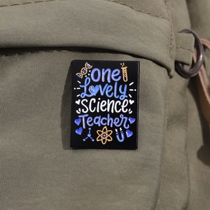 Nahaufnahme der Emaille-Anstecknadel für Chemielehrer mit DNA-Motiv auf einem Rucksack