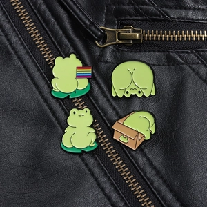 Detail of four green cartoon frog enamel pins styled on a black leather jacket lapel