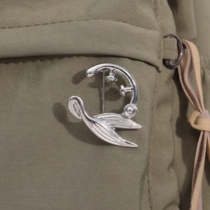 Detailansicht einer silbernen geometrischen Brosche an einem grünen Rucksack