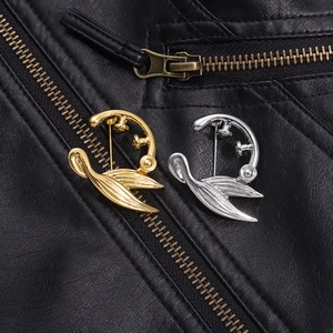Detailansicht geometrischer Legierungs-Broschen in Gold und Silber auf Lederjacke