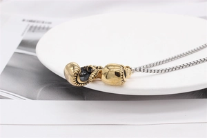 Detailed top view of retro gold and silver boxing glove pendant on a silver box chain