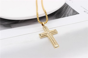 Gros plan détaillé d'un pendentif croix doré avec motif tressé sur une chaîne box