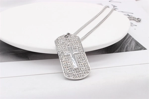 Détail du pendentif croix argenté serti de strass blancs brillants sur un support de bijoux