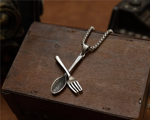 Detail van de vintage stalen lepel en vork hanger ketting op een antieke houten kist