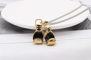 Macro detail of golden boxing glove pendants with black enamel on a silver box chain