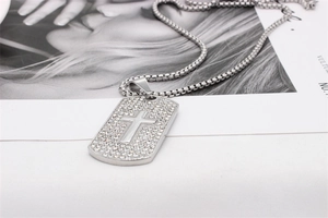 Gros plan du collier dog tag hip-hop avec croix sertie de strass et chaîne maille vénitienne