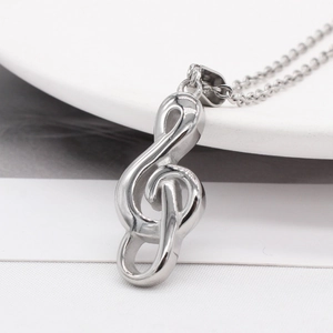 Sleek silver treble clef pendant necklace on a minimalist white ceramic tray