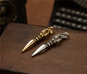 Macro detail of gold and silver phurba dagger pendants on a vintage wooden case