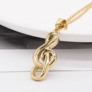Minimalist gold musical note necklace with a G-clef pendant on a white ceramic tray