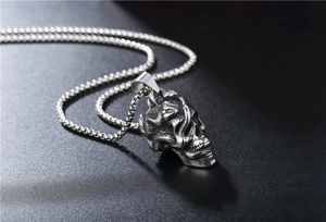 Détail du pendentif crâne et serpent en acier vintage avec une chaîne à billes argentée