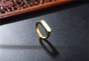 Detailed side view of a geometric gold titanium ring with a rectangular white shell inlay