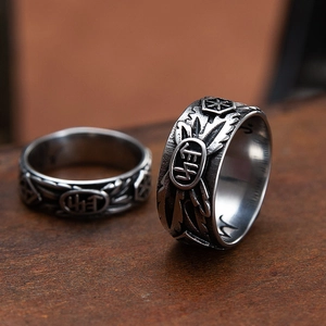 Vintage oxidized stainless steel skull rings with engraved totems on dark wood surface