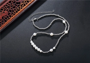 Détail d'un collier de perles argentées avec perles blanches sur fond sombre