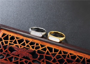 Detailed view of geometric shell inlay rings in gold and silver on wood background
