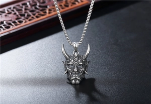 Detailed side view of vintage Hannya mask pendant in distressed stainless steel finish