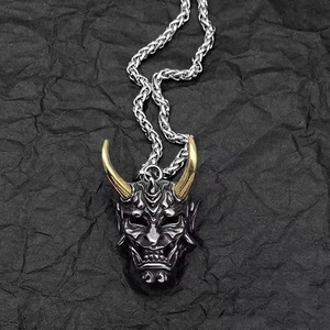Macro shot of vintage Hannya mask pendant with golden horns and silver wheat chain