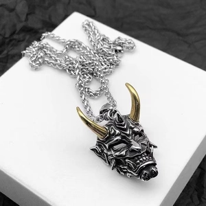 Close-up of vintage Hannya mask pendant with golden horns and detailed Oni carving