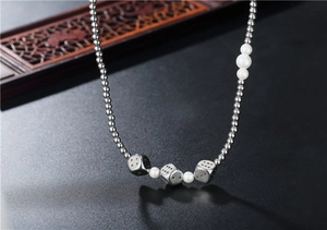 Détail du collier hip hop en acier titane avec dés métalliques et perles blanches de luxe