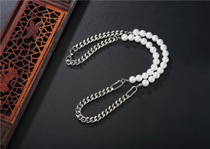 Détail d'un collier hybride chaîne cubaine et perles blanches avec connecteur métallique