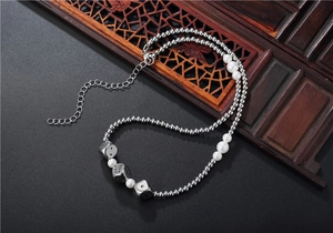 Détail du collier de perles hip-hop avec dés argentés et billes métalliques sur gris
