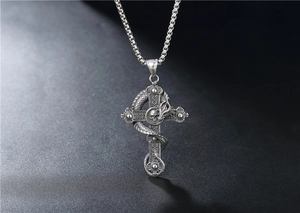 Macro detail of gothic dragon wrapped around a cross pendant with skull emblem
