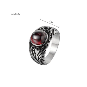 Dettaglio macro di un anello vintage in acciaio inossidabile con gemma rossa e rilievi