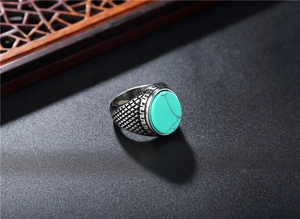 Détail macro d'une bague vintage en acier avec turquoise ovale et motifs grecs