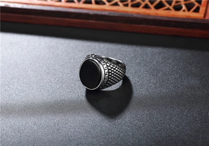 Détail d'une bague rétro en acier inoxydable avec pierre noire et motifs de grecques