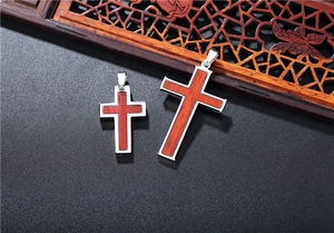 Detail of stainless steel cross pendants with wood inlay on a textured black background