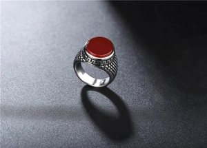 Détail macro d'une bague en acier pour homme avec pierre rouge et maille latérale