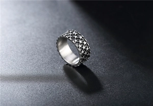 Makroaufnahme von Vintage-Edelstahlring mit geprägten Sternen und Punk-Zahnradkante