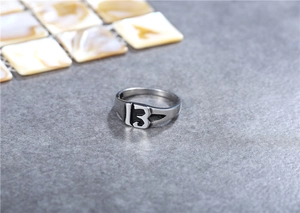 Detalle de un anillo gótico de acero inoxidable con el número 13 sobre un fondo grisáceo