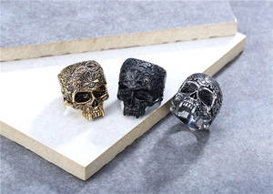 Close-up of vintage skull rings in gold, black, and silver with detailed relief carvings