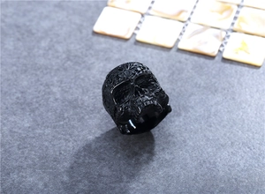 Detail of vintage black skull ring with intricate gothic floral engravings and punk design
