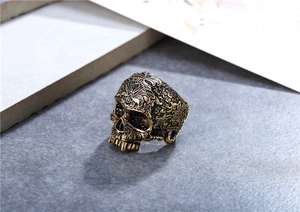 Close-up of vintage rock skull ring with intricate floral carvings and bronze finish
